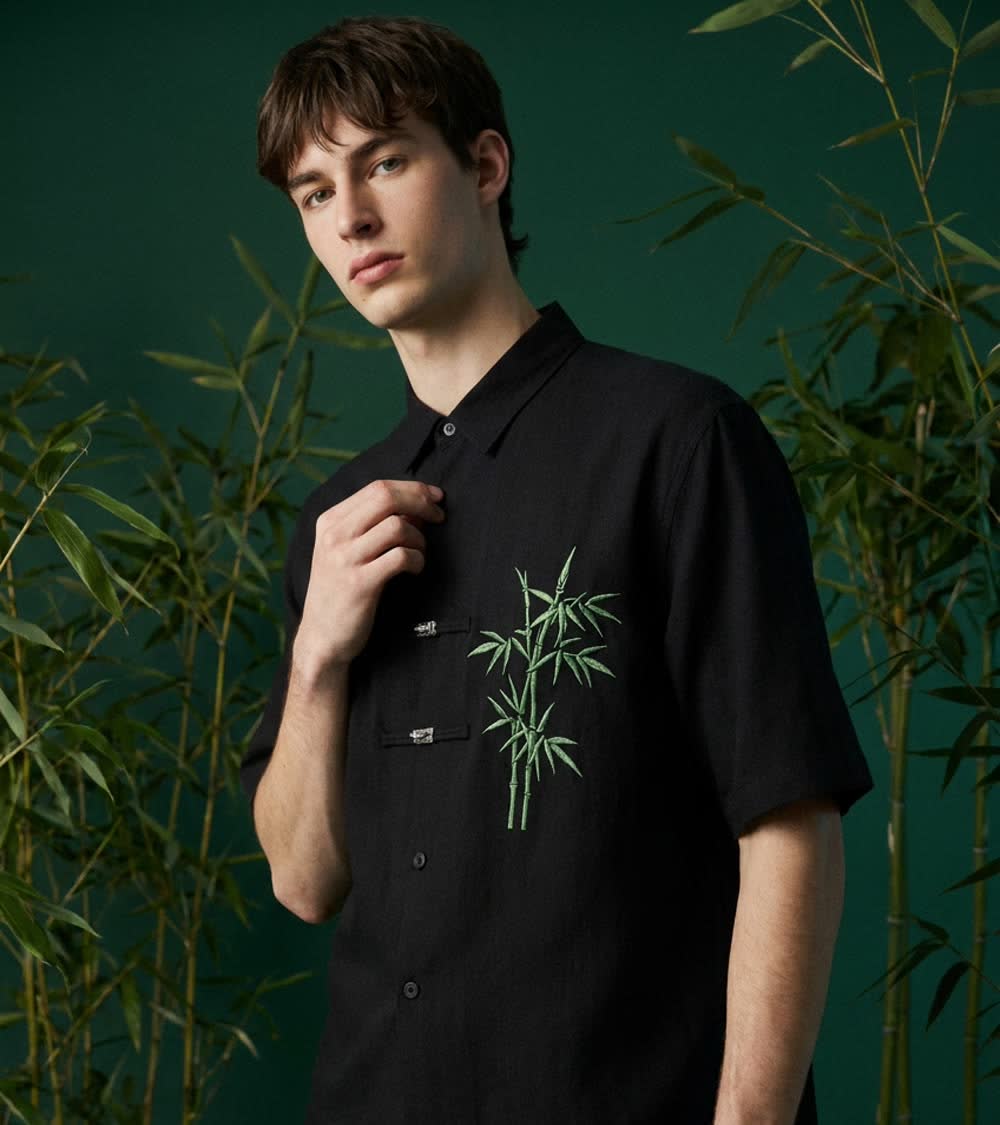 Camicia nera con bambù ricamato davanti a una parete verde