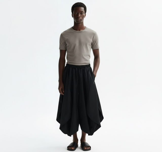 Petal hem asymmetrical pants on model in black, front view