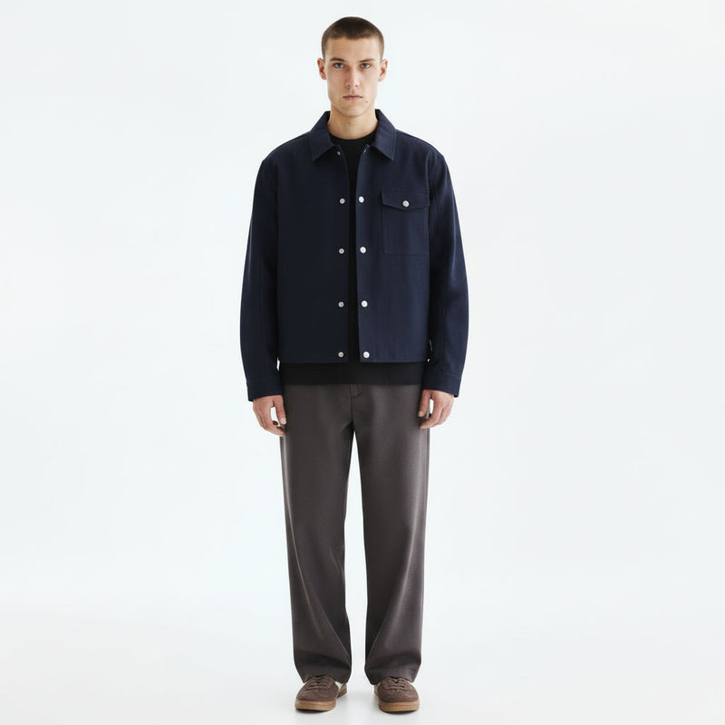An indigo kendo haori jacket hanging open over a dark base layer