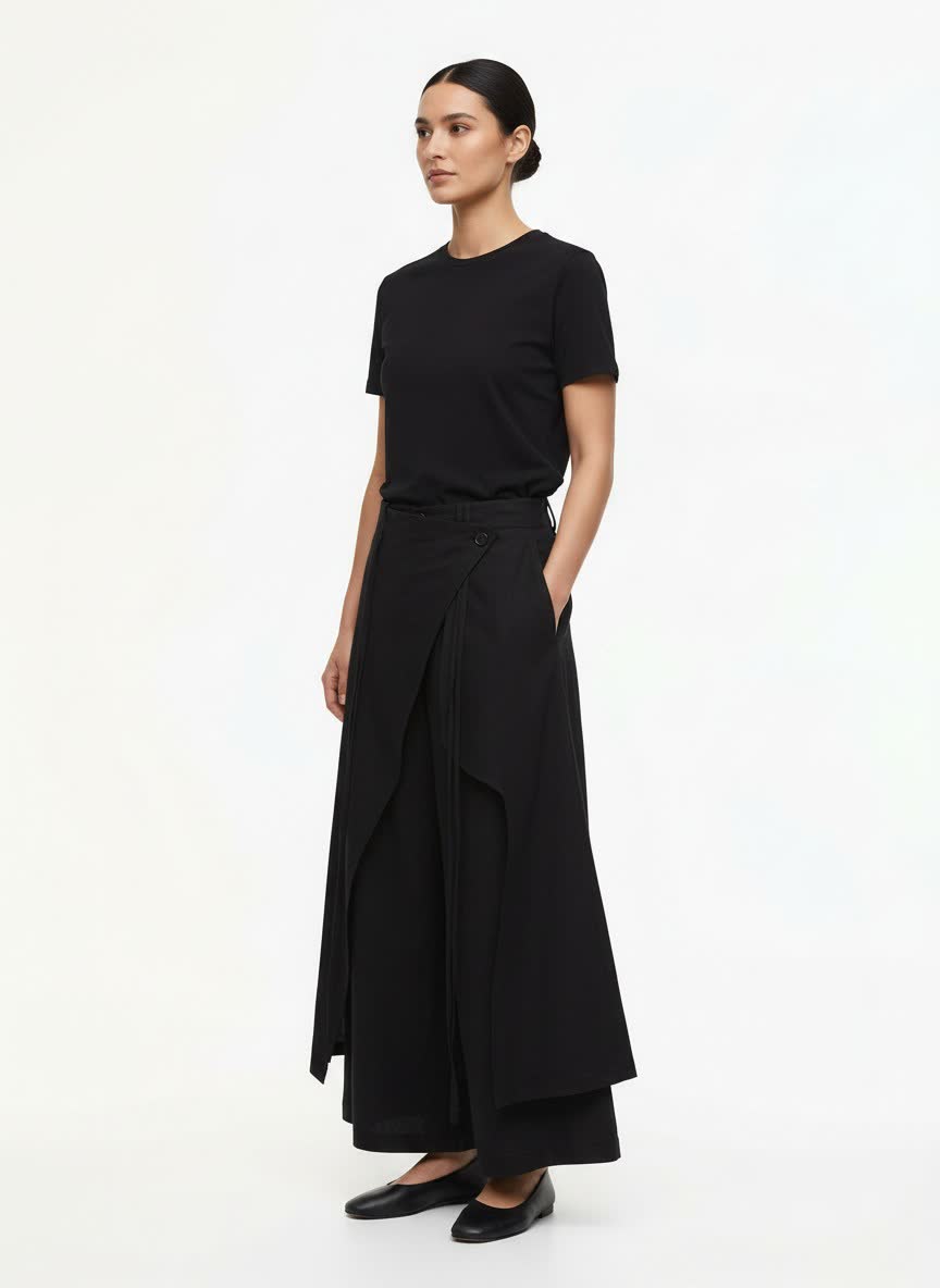 A woman wearing the black hakama pants, three-quarter view: the wrap panel over the wide leg