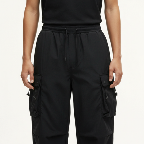 Parachute Cargo Pants on model in black, detail view of the drawstring waist and cargo pockets
